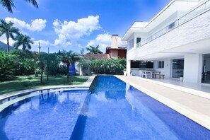Ein modernes Haus mit Pool, Terrasse und Blick ins grüne Umland.