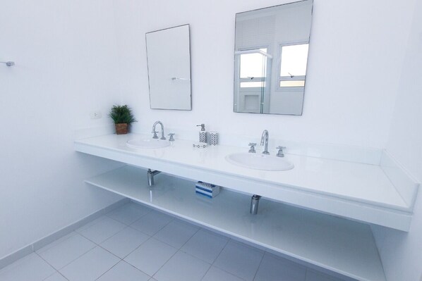 Ein modernes Badezimmer mit zwei Waschbecken, einem großen Spiegel und einem kleinen Topfpflanzen.