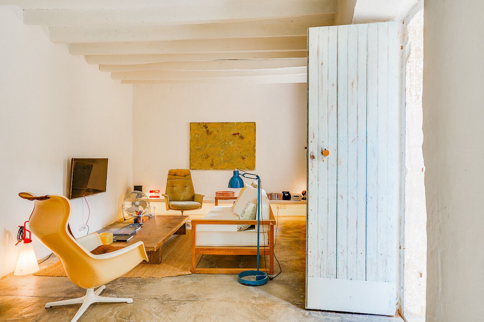 Een kamer met een houten eettafel, een bank, een stoel, een lamp en een televisie.