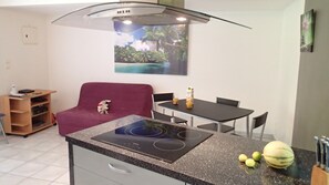 Une cuisine de taille réduite avec un îlot central, une table à manger et un canapé.