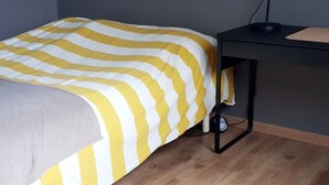 Un dormitorio con una cama, un escritorio y una lámpara de escritorio.