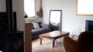 Una sala de estar con sofá, mesa de centro, televisor y chimenea.