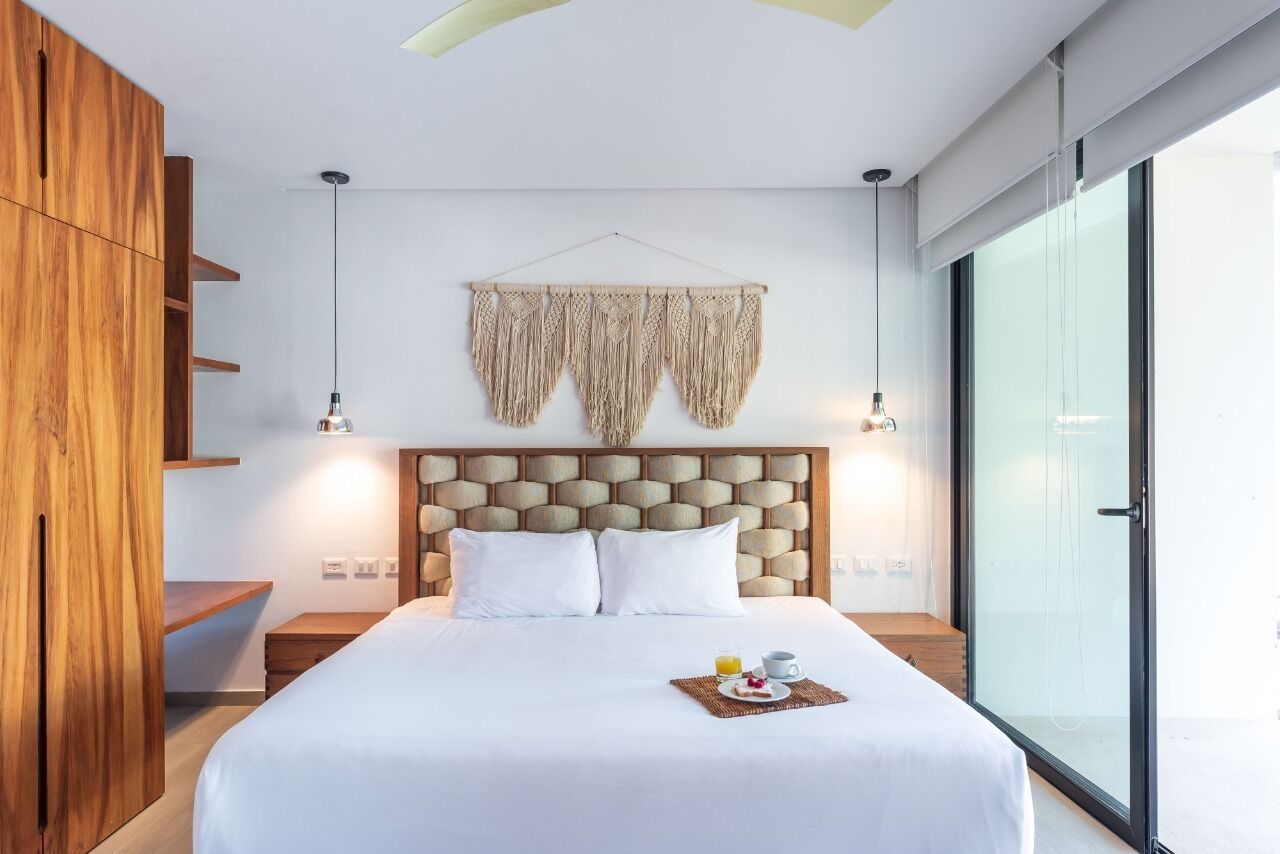 Moderni hotellihuone, jossa on suuri sänky, puinen vaatekaappi ja iso ikkuna.