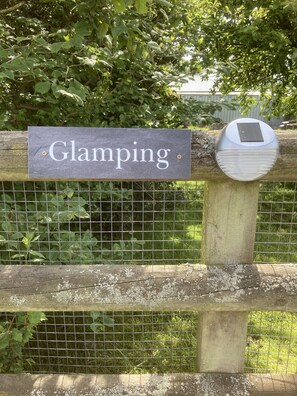 A sign reading "Glamping" attached to a wooden fence with a solar panel. - Glamping at The Homestead - Ensuite Bell Tent - Campsite (Hereford)