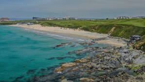 A coastal beach with rocky shores, a sandy beach, and buildings in the background. - Fistral Lookout - Parking, WiFi & Sea View (Newquay)