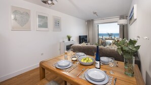 A modern bedroom with a bed, a TV, and a balcony with a view of the sea. - Fistral Lookout - Parking, WiFi & Sea View (Newquay)