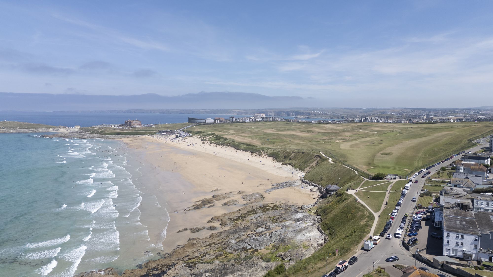 A coastal town with a beach, a golf course, and residential buildings.