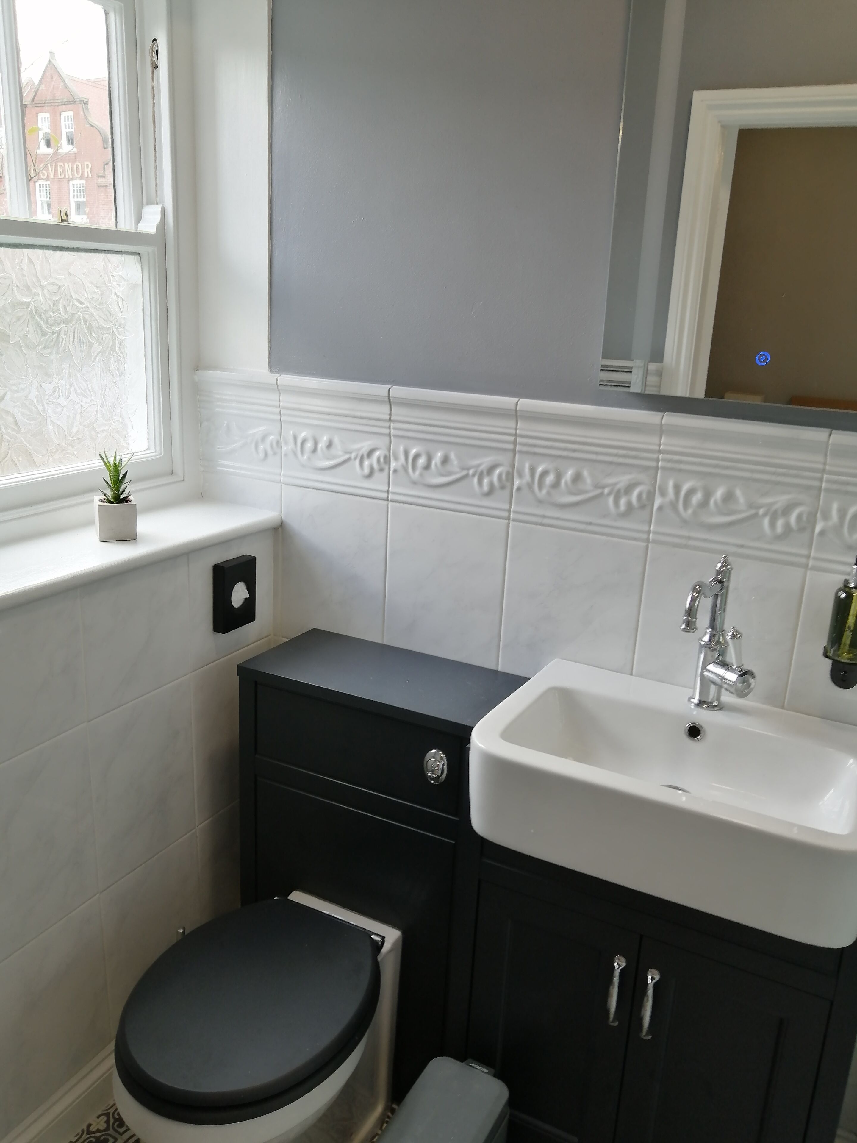 A bathroom with a toilet, sink, and cabinet.