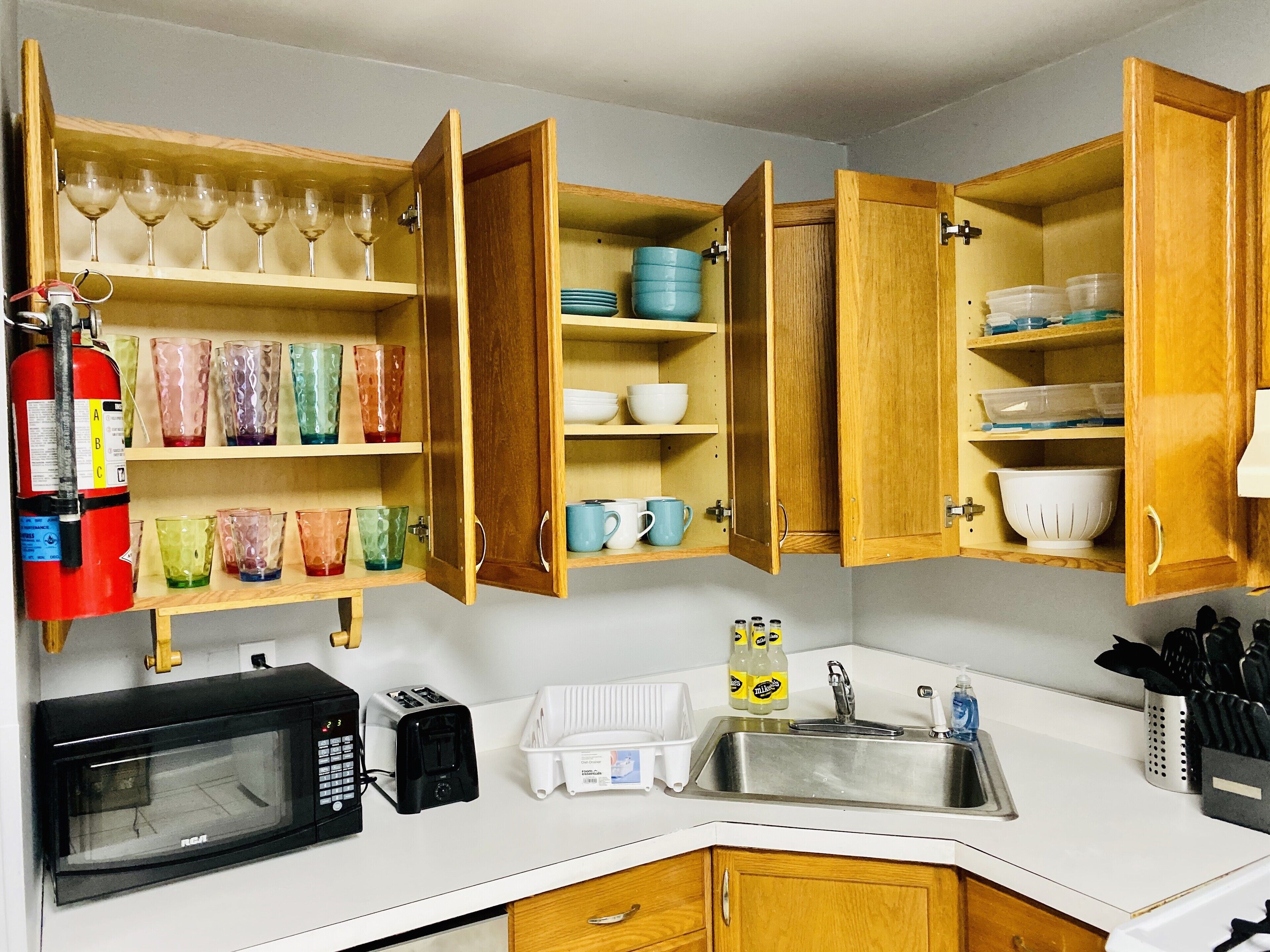A compact kitchen with wooden cabinets, a microwave, a toaster, and a sink.