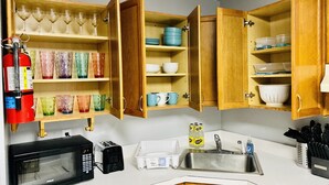 A compact kitchen with wooden cabinets, a microwave, a toaster, and a sink.