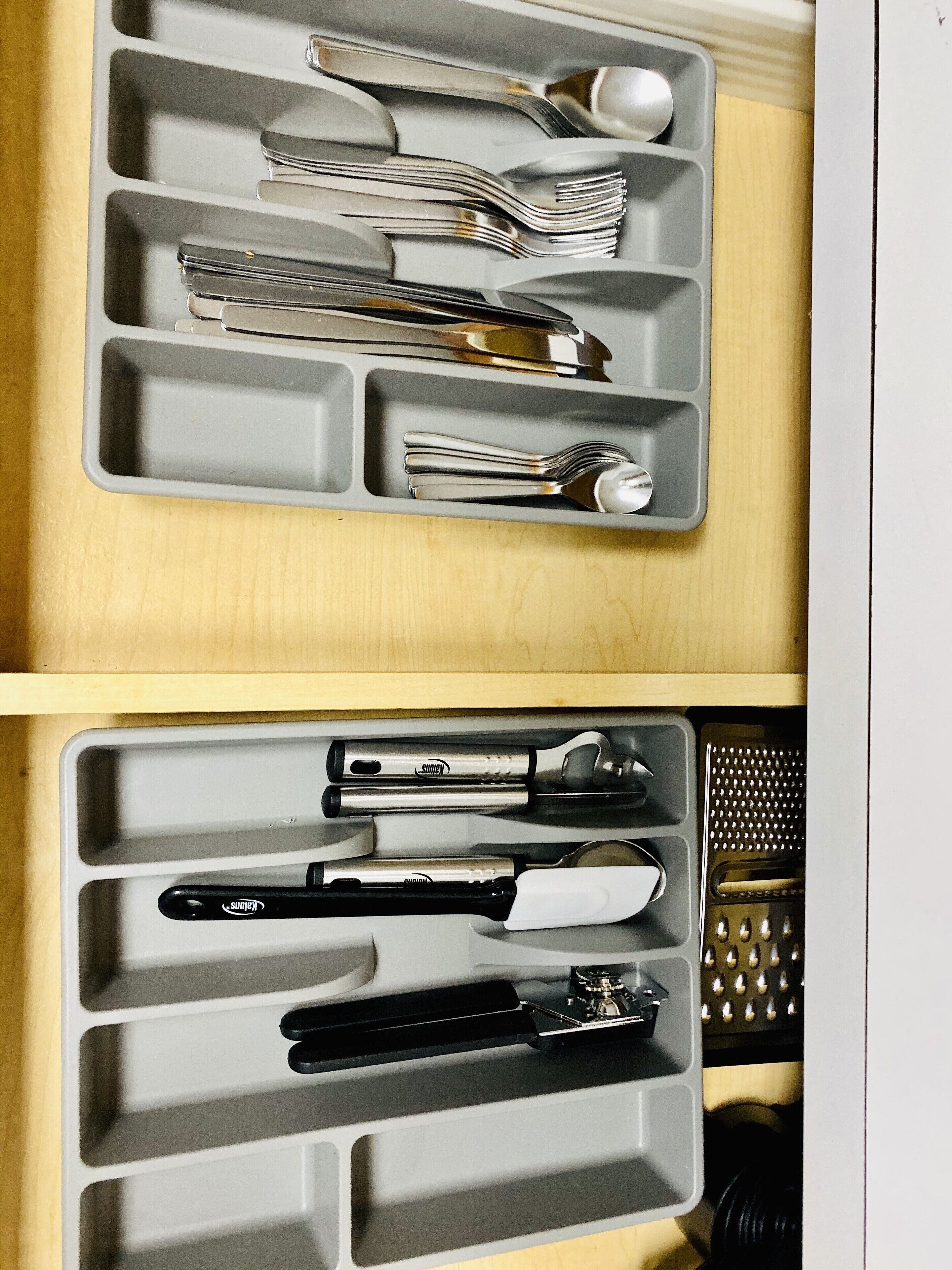 A drawer with compartments containing various kitchen utensils.