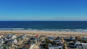 A coastal residential area with houses near the beach, a clear sky, and the ocean.