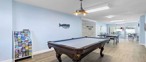 A pool table in a room with light blue walls, a wooden floor, and a ceiling light fixture.