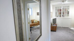 Een kamer met een grote spiegel, een bank, een boekenkast en een bureau.