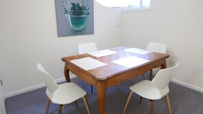 Una mesa de comedor con cuatro sillas blancas, una mesa de madera y un cuadro en la pared.