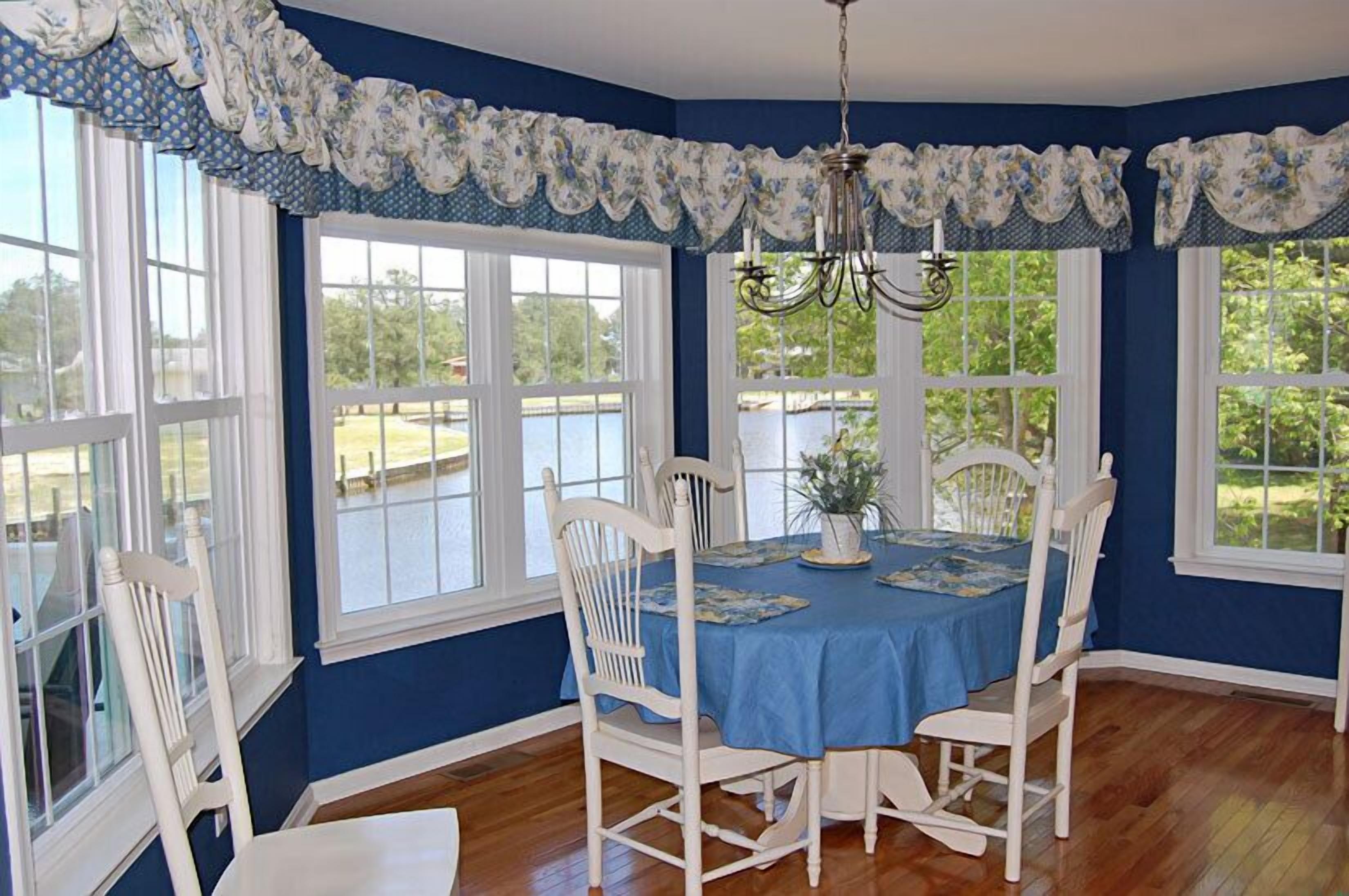 A dining room with a blue tablecloth, white chairs, and a chandelier.