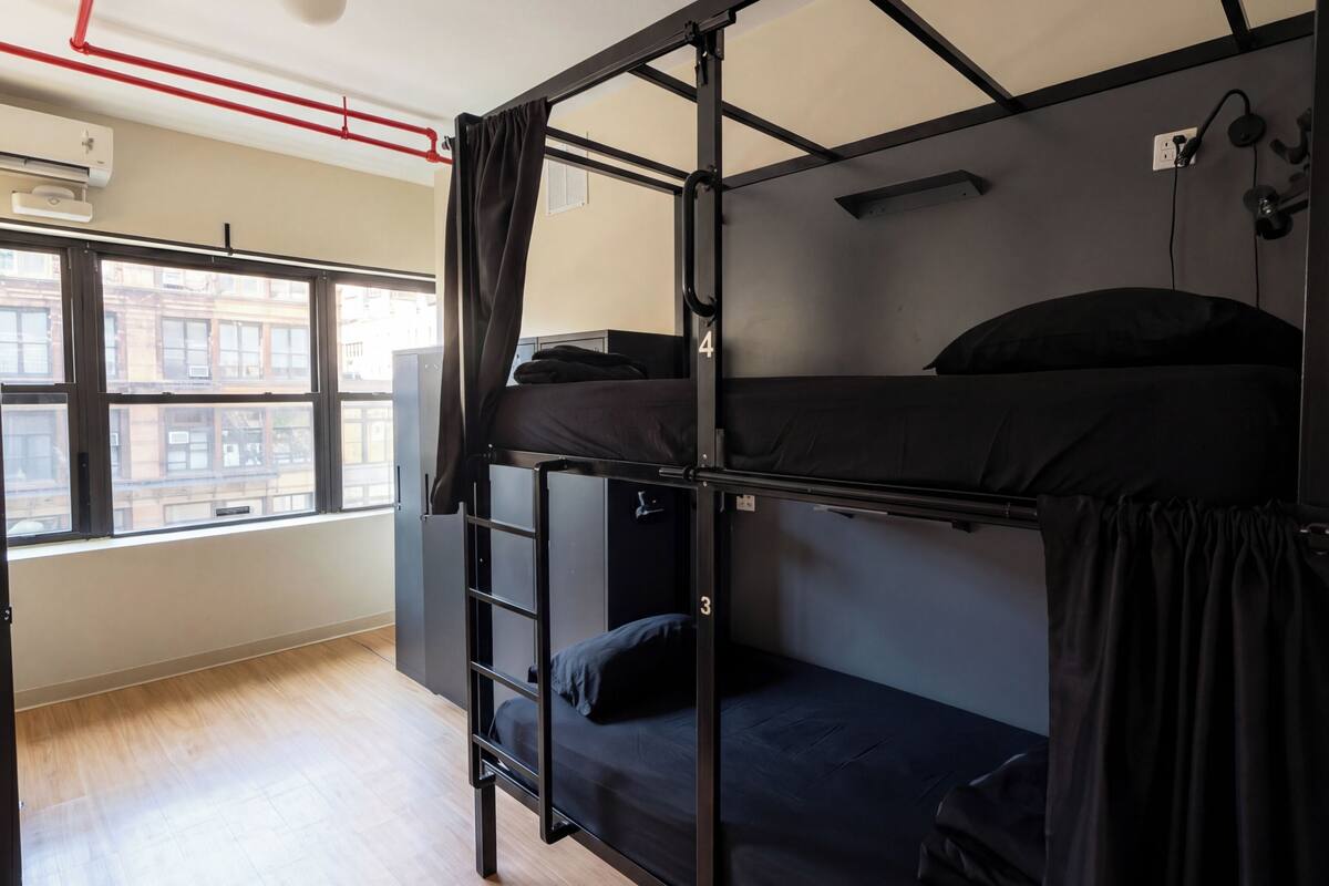 A bunk bed room with a window, a ladder, and a ceiling light fixture.