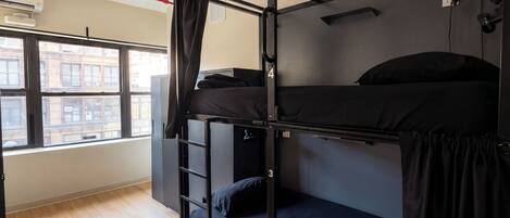 A bunk bed room with a window, a ladder, and a ceiling light fixture.