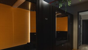 Una habitación de hotel moderna con un armario de madera oscura, un sofá negro y una cama pequeña.