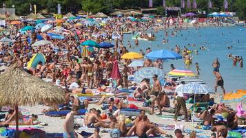 Guests can enjoy a lively beach experience with access to shaded areas and a nearby swimming spot.