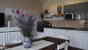 A modern kitchen with white cabinets, a dark countertop, and a vase of flowers on the table. - Apartment in Banjol with Balcony, Air condition, WIFI, Dishwasher (4888-1) (Banjol)