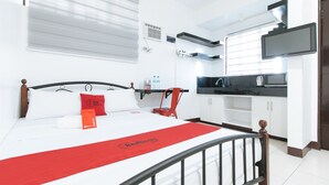 A hotel room with a bed, a red throw, a red chair, a TV, a microwave, and a sink. - Reddoorz @ V-cloud Hills Near De La Salle (Dasmarinas)