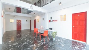 Un vestíbulo espacioso con suelo de mármol, puertas rojas y el letrero de RedDoorz.