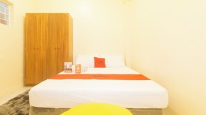 Una habitación de hotel con una cama, un armario de madera y una silla amarilla.