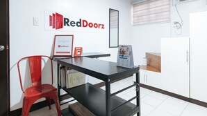 Una oficina pequeña con un escritorio, una silla y un letrero de RedDoorz en la pared.