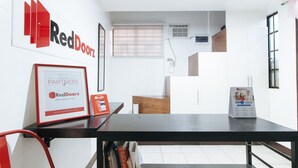 Una habitación de hotel moderna con una mesa negra, un cartel enmarcado de RedDoorz y un folleto de RedDoorz.