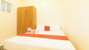 Una habitación de hotel con una cama, un armario de madera, una ventana y un cojín Red Doorz.