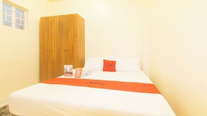 Ein Hotelzimmer mit Bett, einem Holzschrank, einem Fenster und einem Kissen von Red Doorz.