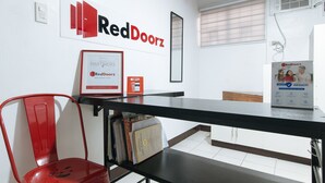 A RedDoorz reception desk with a framed RedDoorz Partners sign, a RedDoorz RedClub sign, and a RedDoorz HygienePass sign. - Reddoorz @ V-cloud Hills Near De La Salle (Dasmarinas)