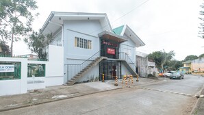 A building with a staircase leading to a balcony, a sign reading "RedBook," and a gated entrance. - Reddoorz @ V-cloud Hills Near De La Salle (Dasmarinas)
