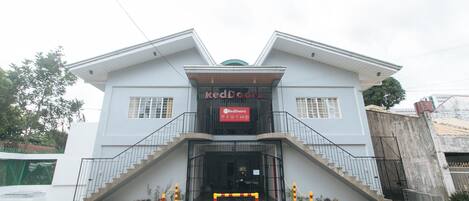 A two-story building with a central entrance, a staircase on each side, and a sign above the entrance.