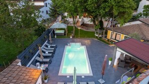 Un área de piscina en la azotea con sillones reclinables y un jacuzzi.