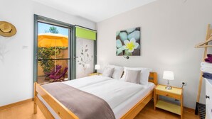 Habitación de hotel con cama, mesitas de noche, una silla, armario y vistas al exterior.
