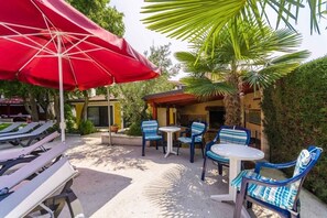 An outdoor patio area with lounge chairs, a table, and a red umbrella. - Apartment in Poreč with Terrace, Air condition, WIFI, Washing machine (4928-8) (Porec)