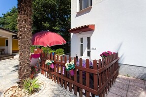 A patio area with a wooden fence, a red umbrella, and potted plants. - Apartment in Poreč with Terrace, Air condition, WIFI, Washing machine (4928-8) (Porec)