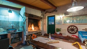 Una cocina rústica con estufa de leña, una mesa de comedor con camino de mesa y una puerta verde.
