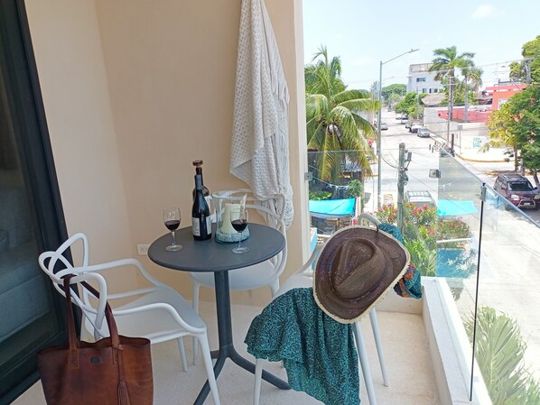 Un balcon avec une table dressée pour deux personnes, une bouteille de vin et une bougie. Il y a des chaises et un sac à main sur la table.