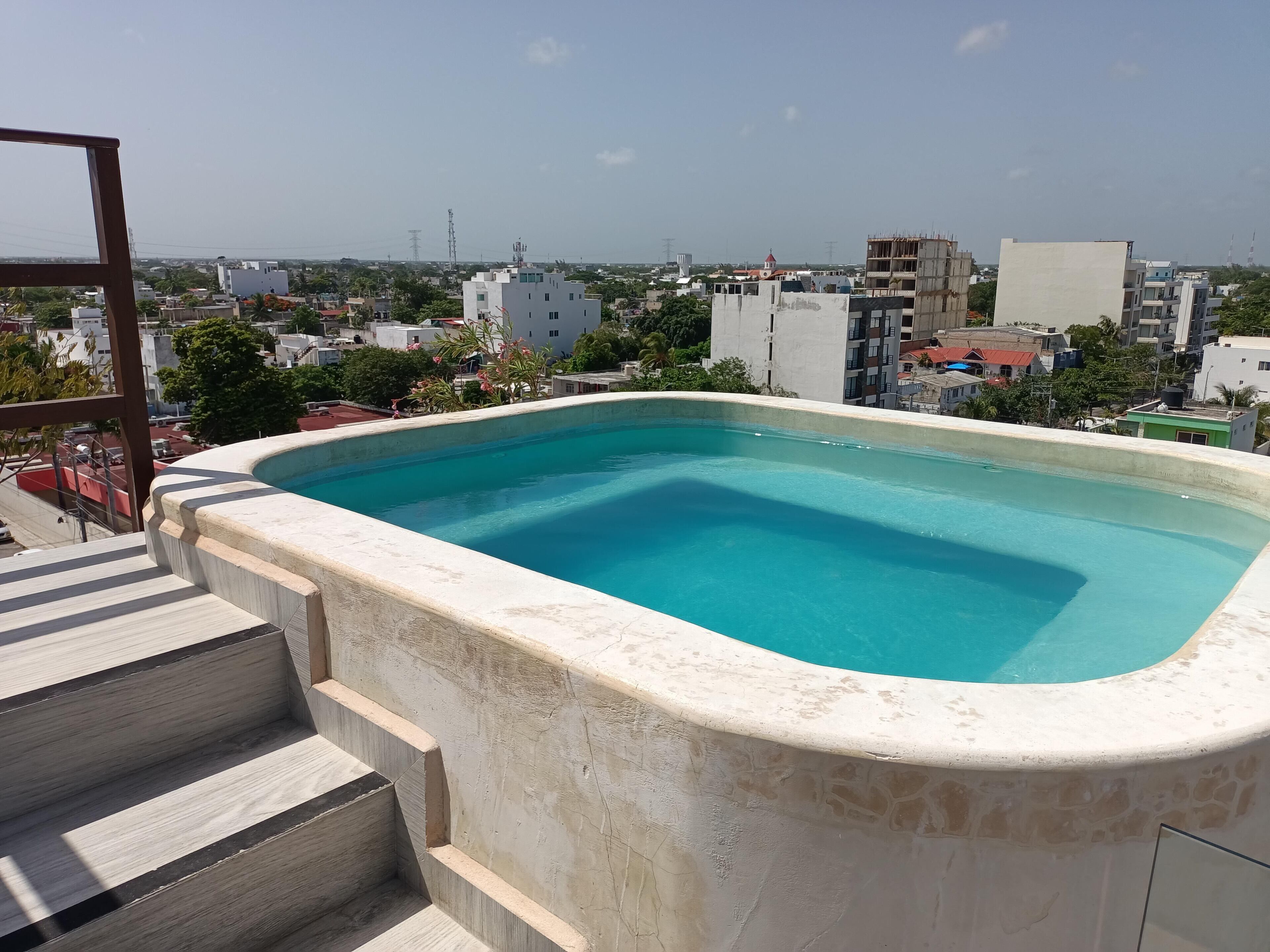A rooftop swimming pool with a view of the cityscape.
