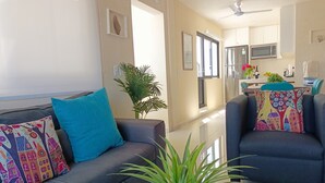 A modern living room with a grey sofa, teal cushions, and a potted plant. - Polo 54 Downtown Apartments (Playa del Carmen)