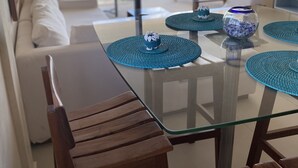A modern dining area with a glass table, wooden chairs, and blue woven placemats. - Polo 54 Downtown Apartments (Playa del Carmen)