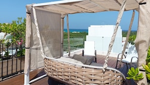 A wicker swing chair with a canopy, overlooking a cityscape and the sea. - Polo 54 Downtown Apartments (Playa del Carmen)