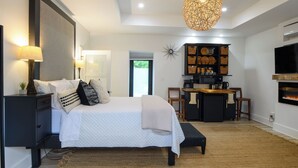 A modern bedroom with a large bed, bedside tables, a desk, and a fireplace. - Escape WithInn-Relaxation Centrally Located to Beaches and Walkable Restaurants (Harbert)