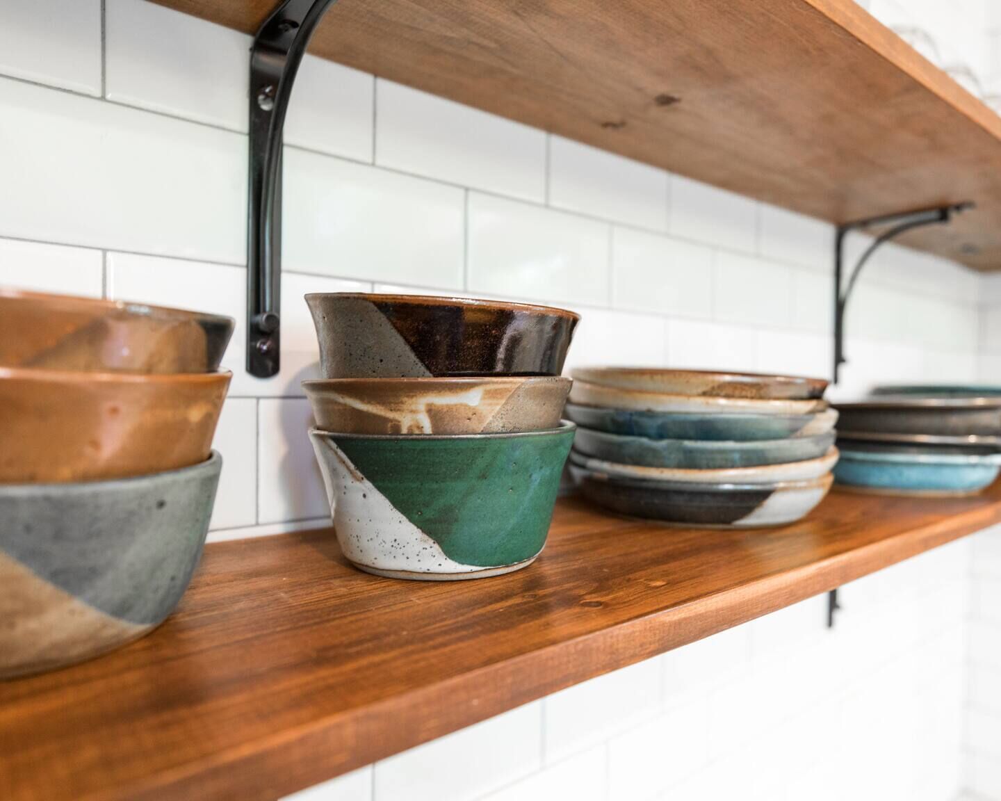 A kitchen shelf with various ceramic bowls and plates.