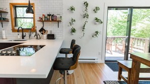 Una cocina moderna con una isla blanca, taburetes negros y un amplio ventanal.