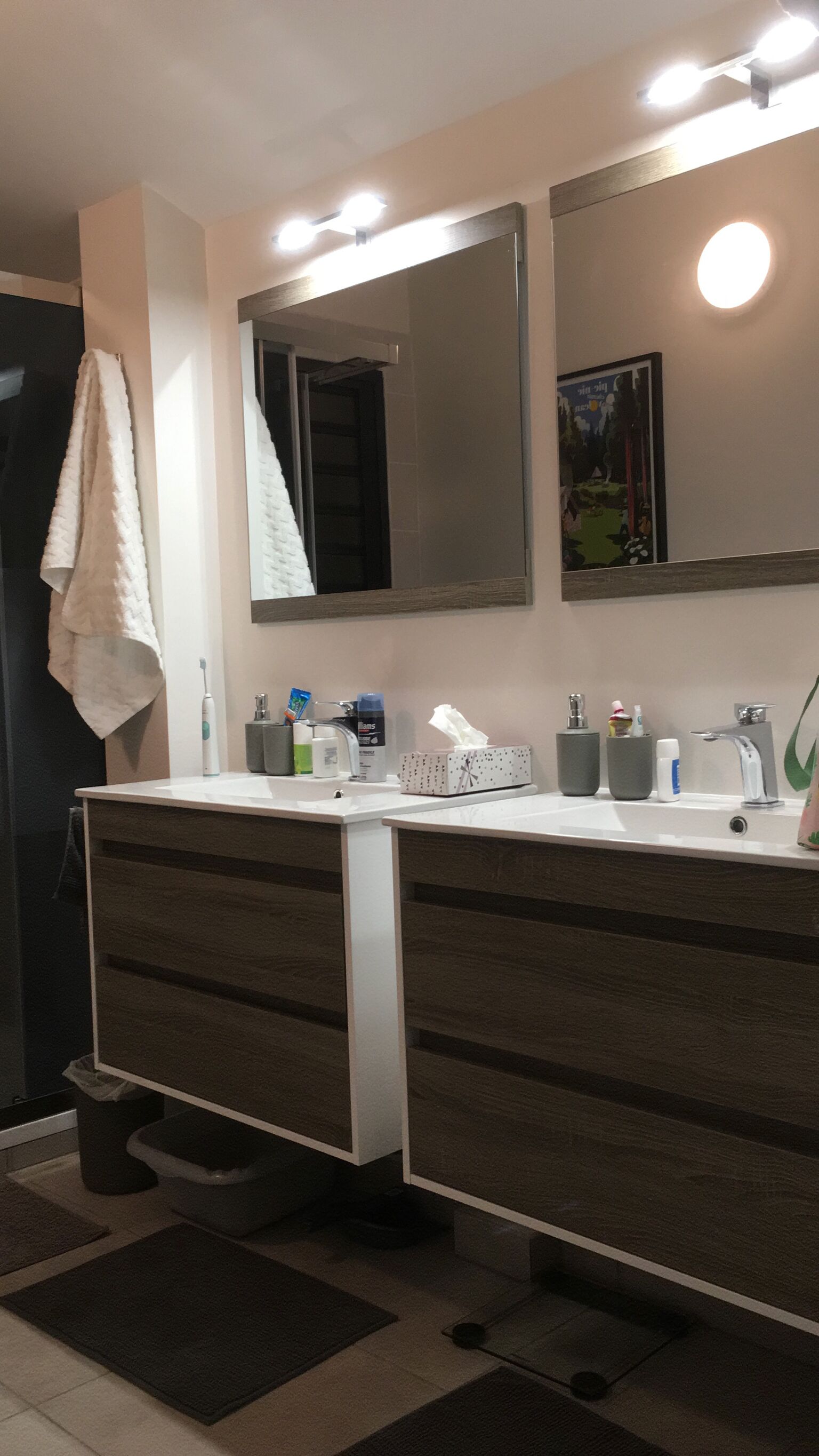 A modern bathroom with a large mirror, a white sink, and a dark-toned vanity.