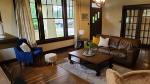 Una sala acogedora con un sofá de cuero marrón, un sillón azul y una mesa de centro de madera.